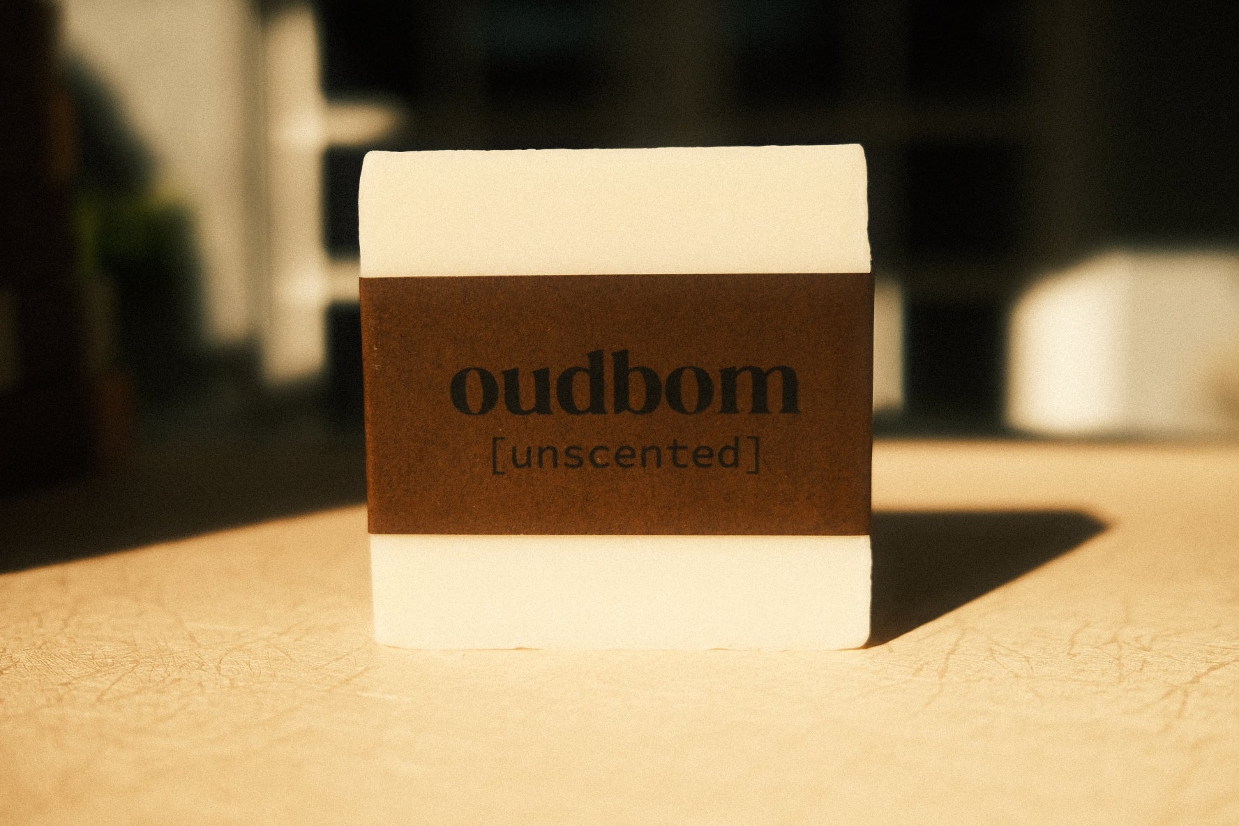 Bar of white soap with a brown label, “oudbom, unscented”