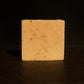 Tan bar of soap standing with brown background