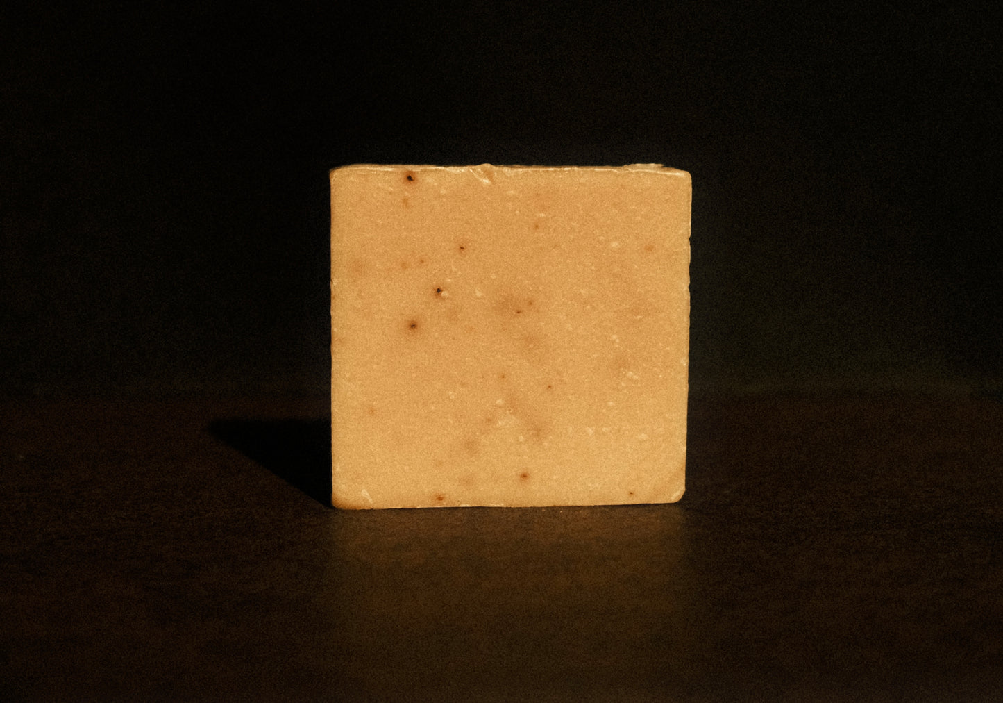 Tan bar of soap standing with brown background