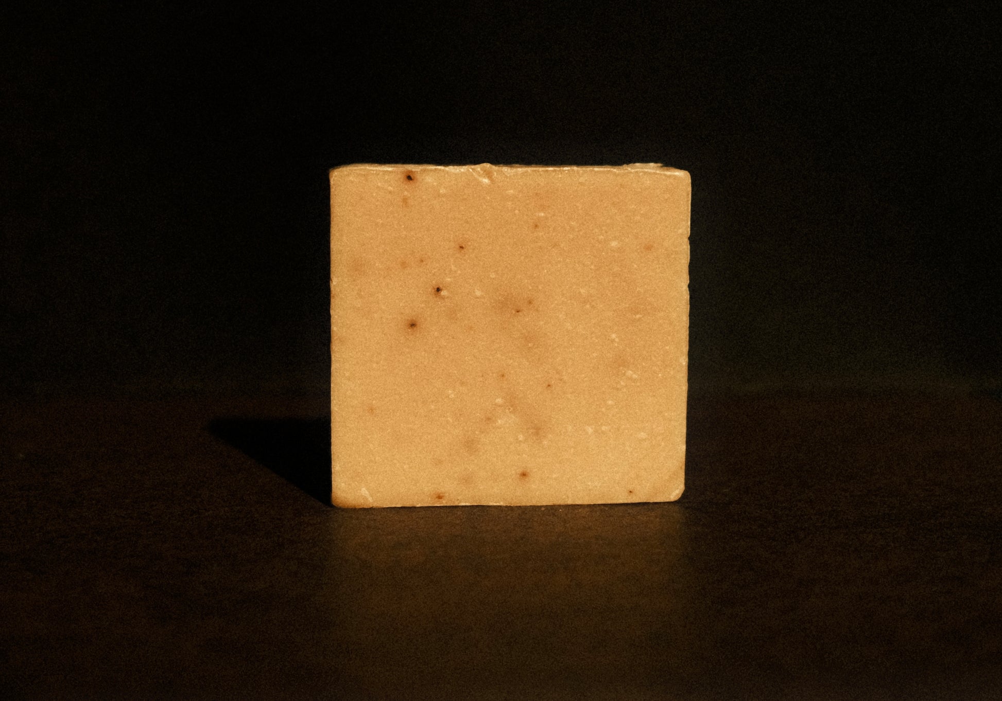 Tan bar of soap standing with brown background