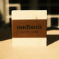 Bar of off-white soap with a brown label, “oudbom, mint tea”