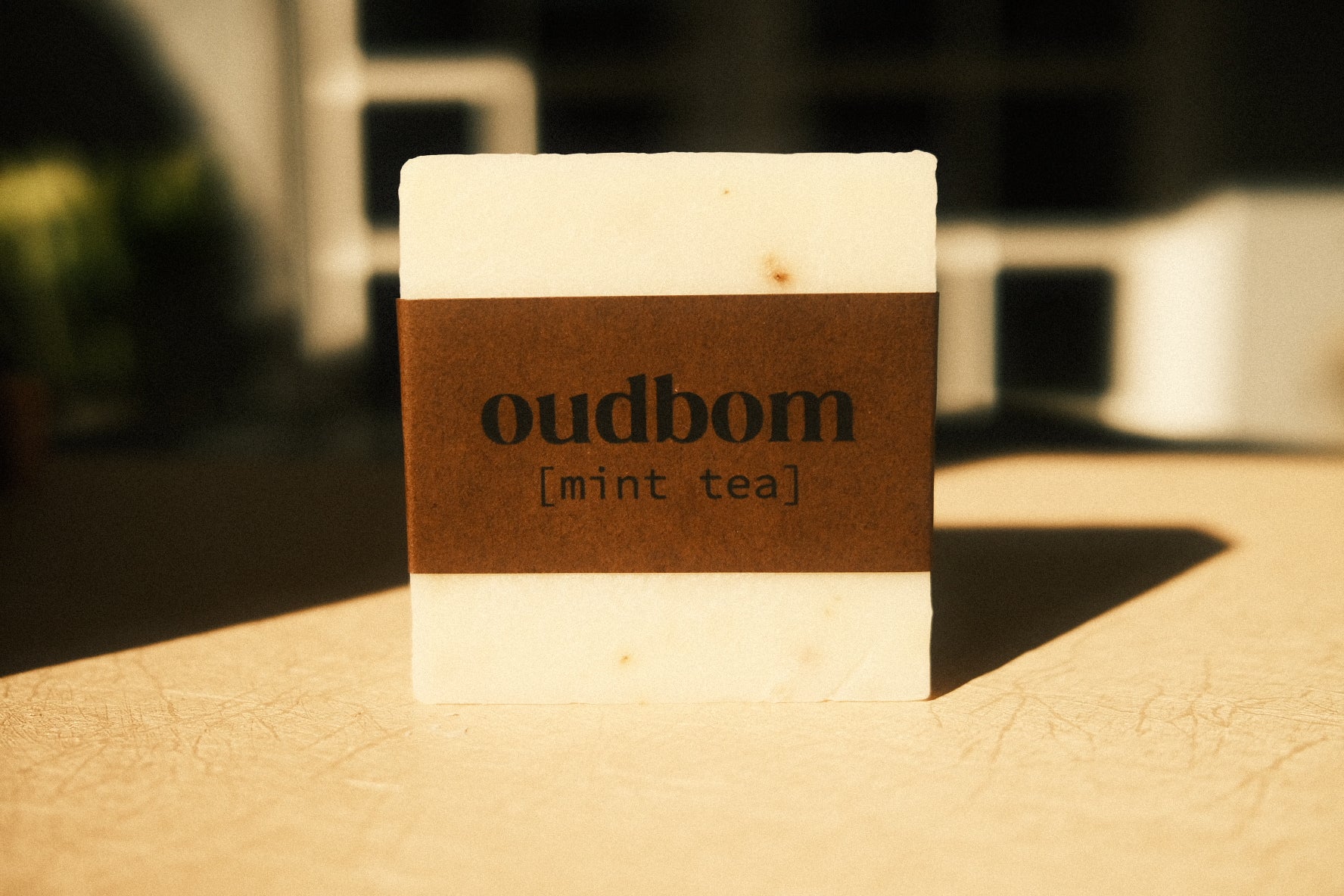 Bar of off-white soap with a brown label, “oudbom, mint tea”