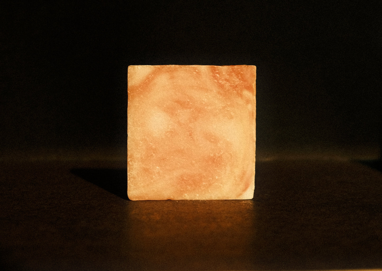 Orange swirled bar of soap standing with brown background