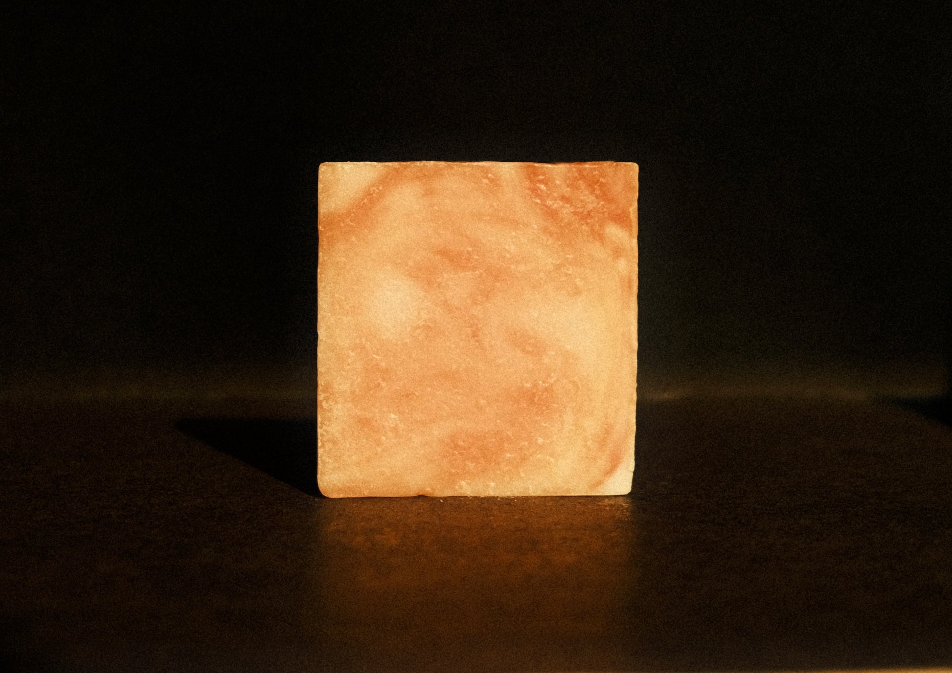 Orange swirled bar of soap standing with brown background