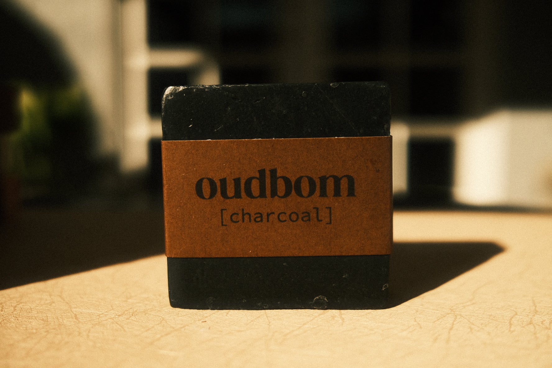 Bar of black soap with a brown label, “oudbom, charcoal”