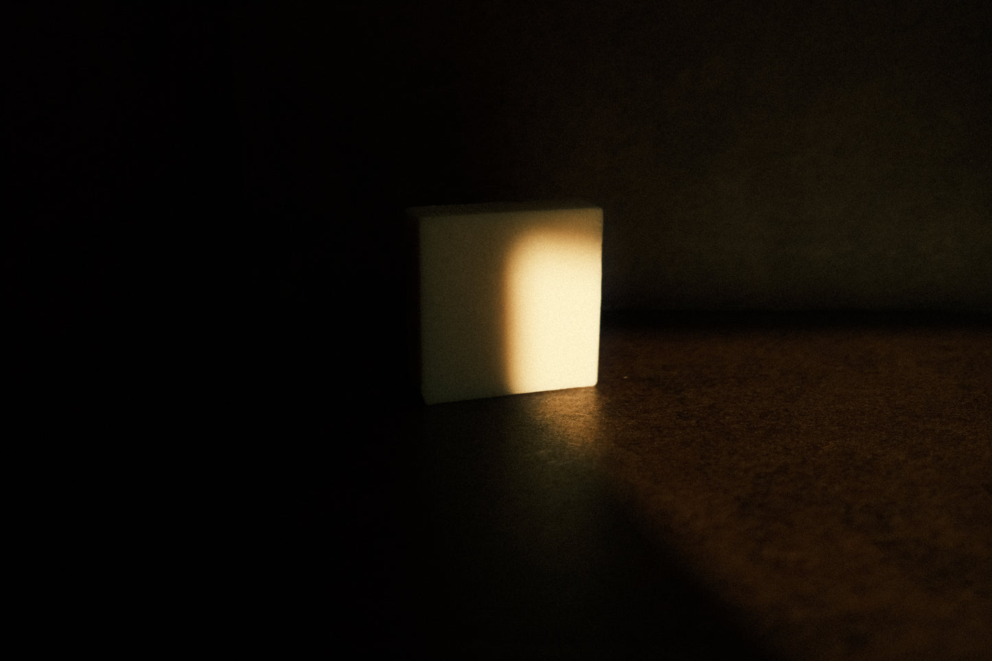 White bar of soap partially illuminated by light, the rest hidden in shadow