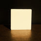 White bar of soap stands with brown floor and background, its reflection shining faintly underneath