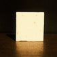 White bar of soap standing with brown background, its reflecting slightly shining underneath