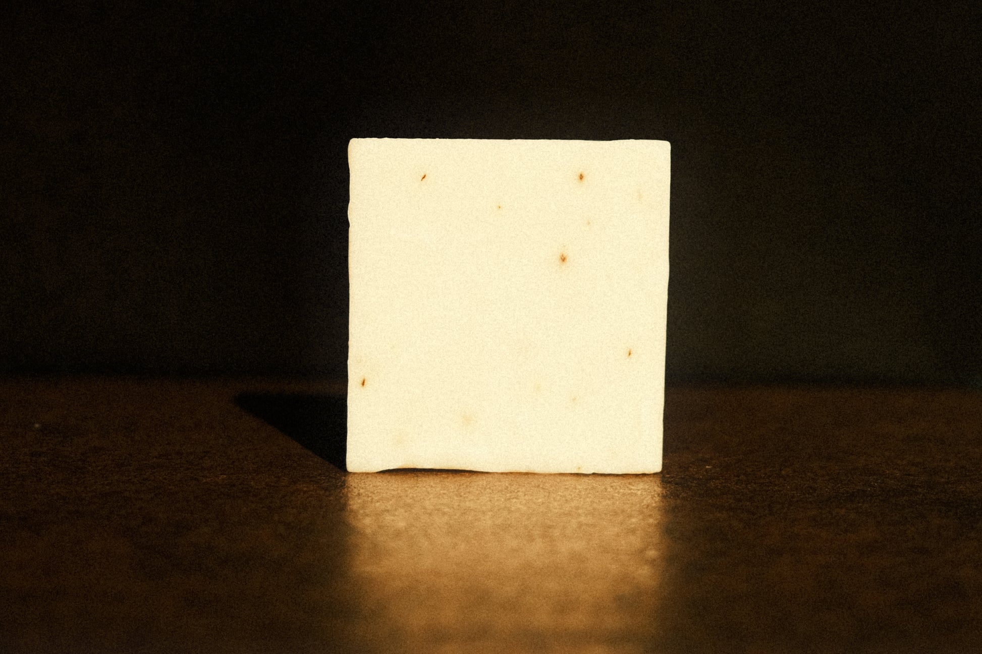 White bar of soap standing with brown background, its reflecting slightly shining underneath