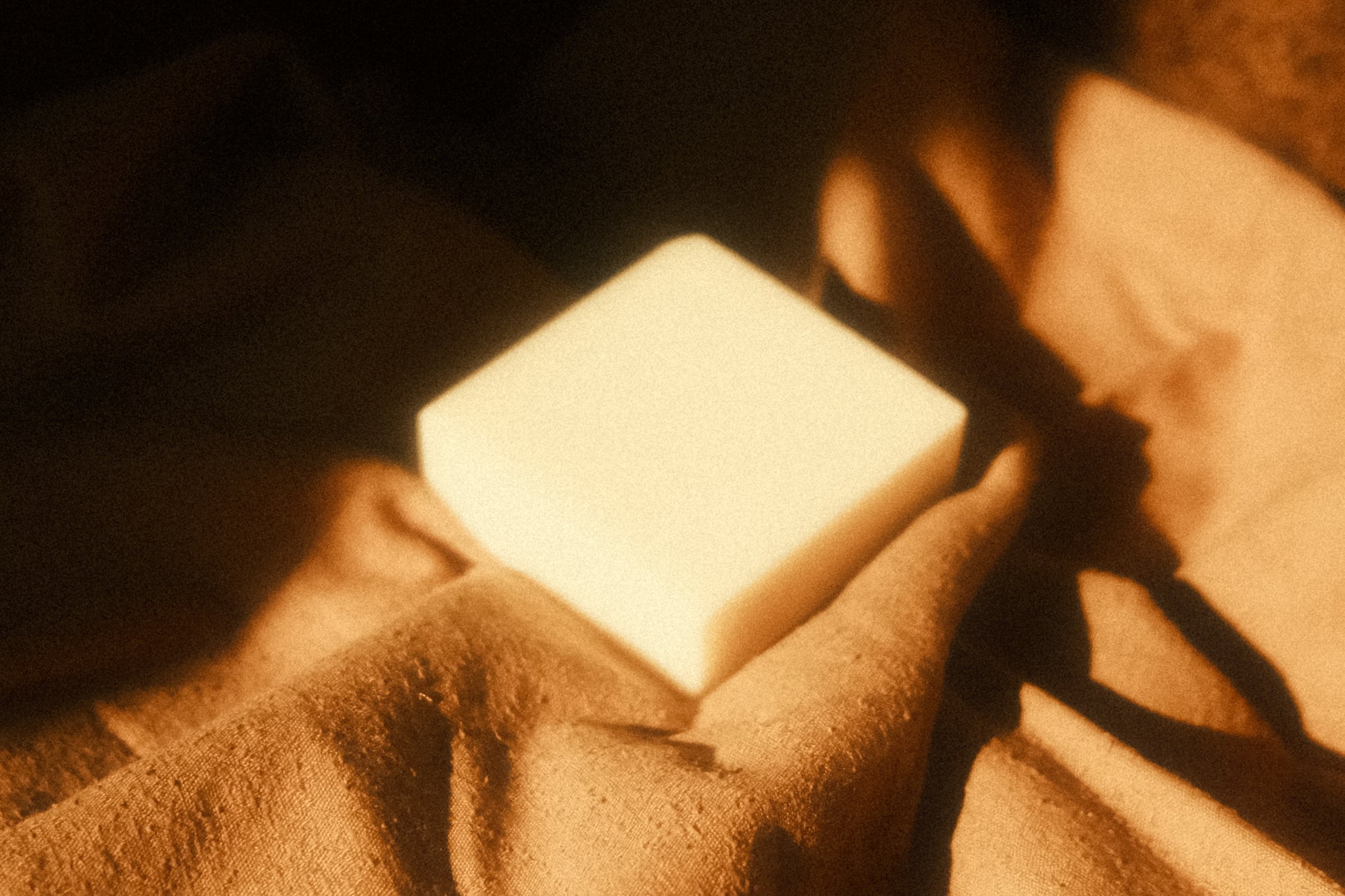 White bar of soap laying on light brown cloth