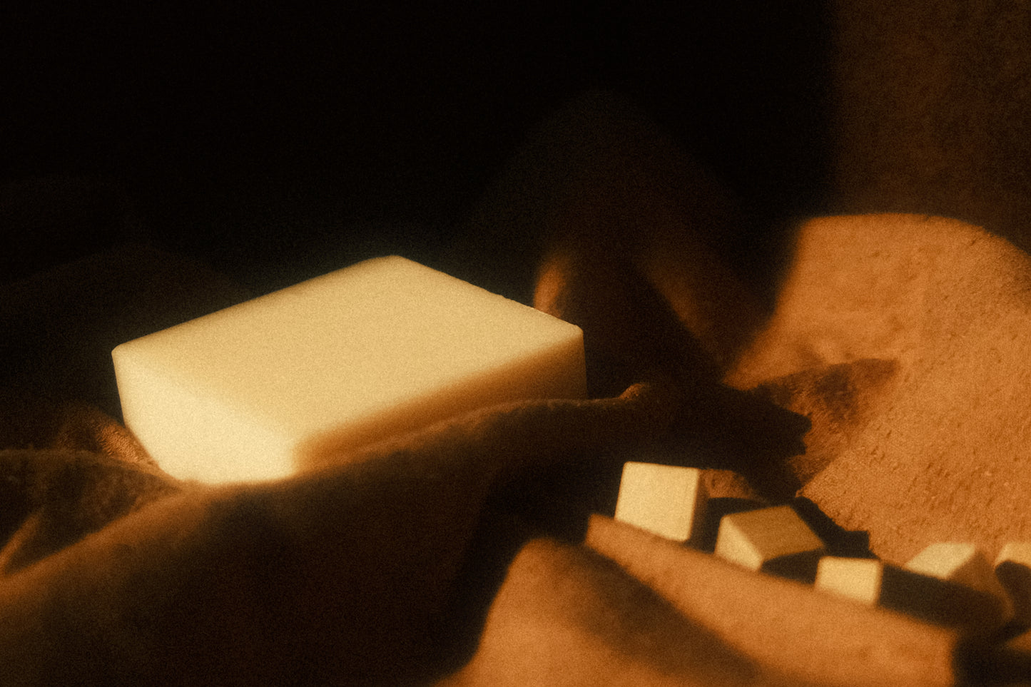 White bar of soap lays on brown cloth with small cubes