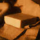 Tan bar of soap laying on light brown cloth