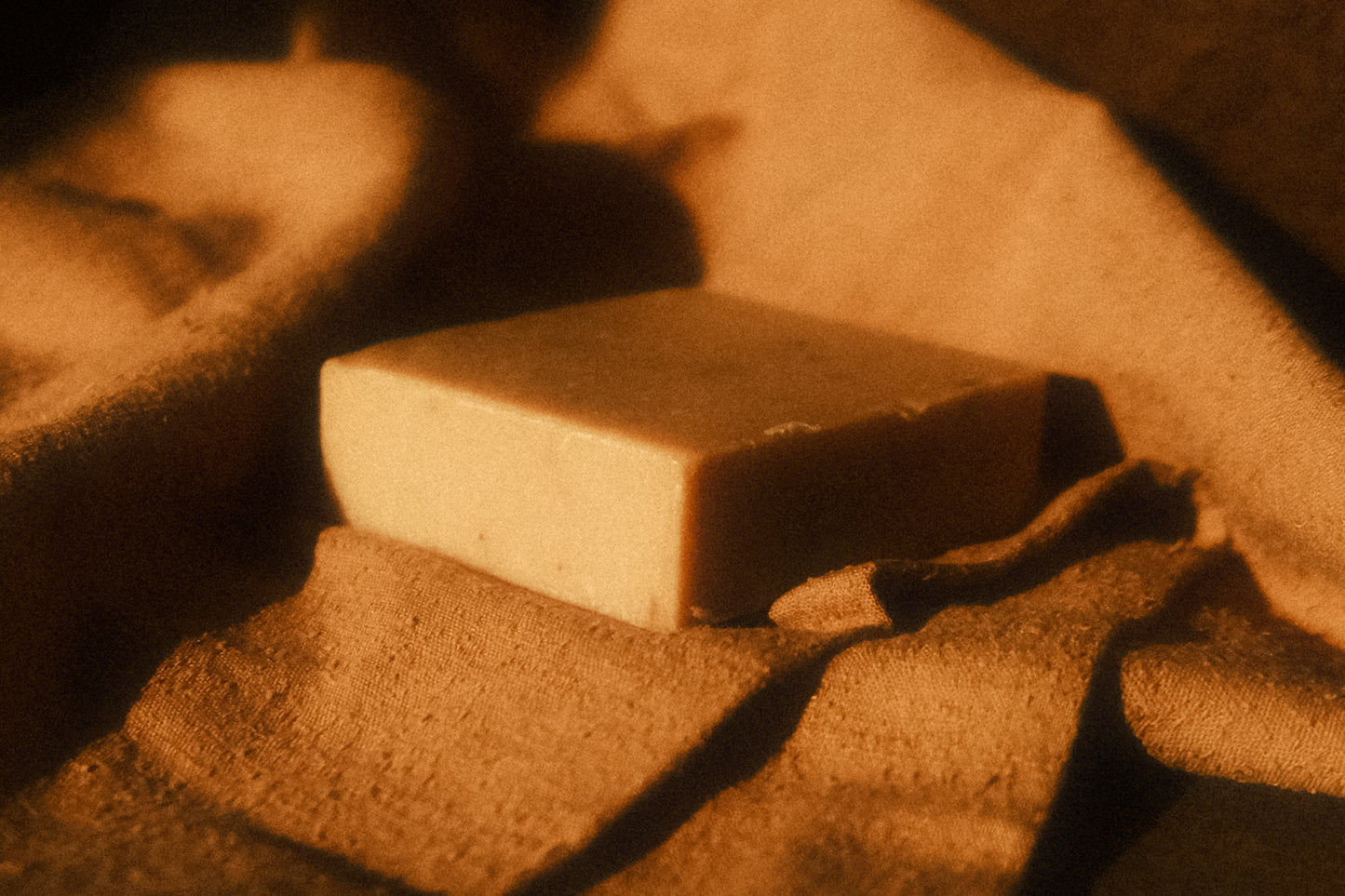 Tan bar of soap laying on light brown cloth