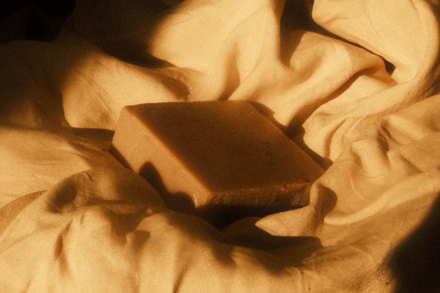 Tan bar of soap laying on beige cloth