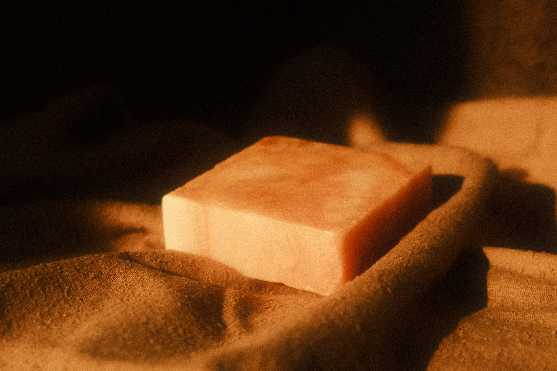 Orange swirled bar of soap laying on brown cloth