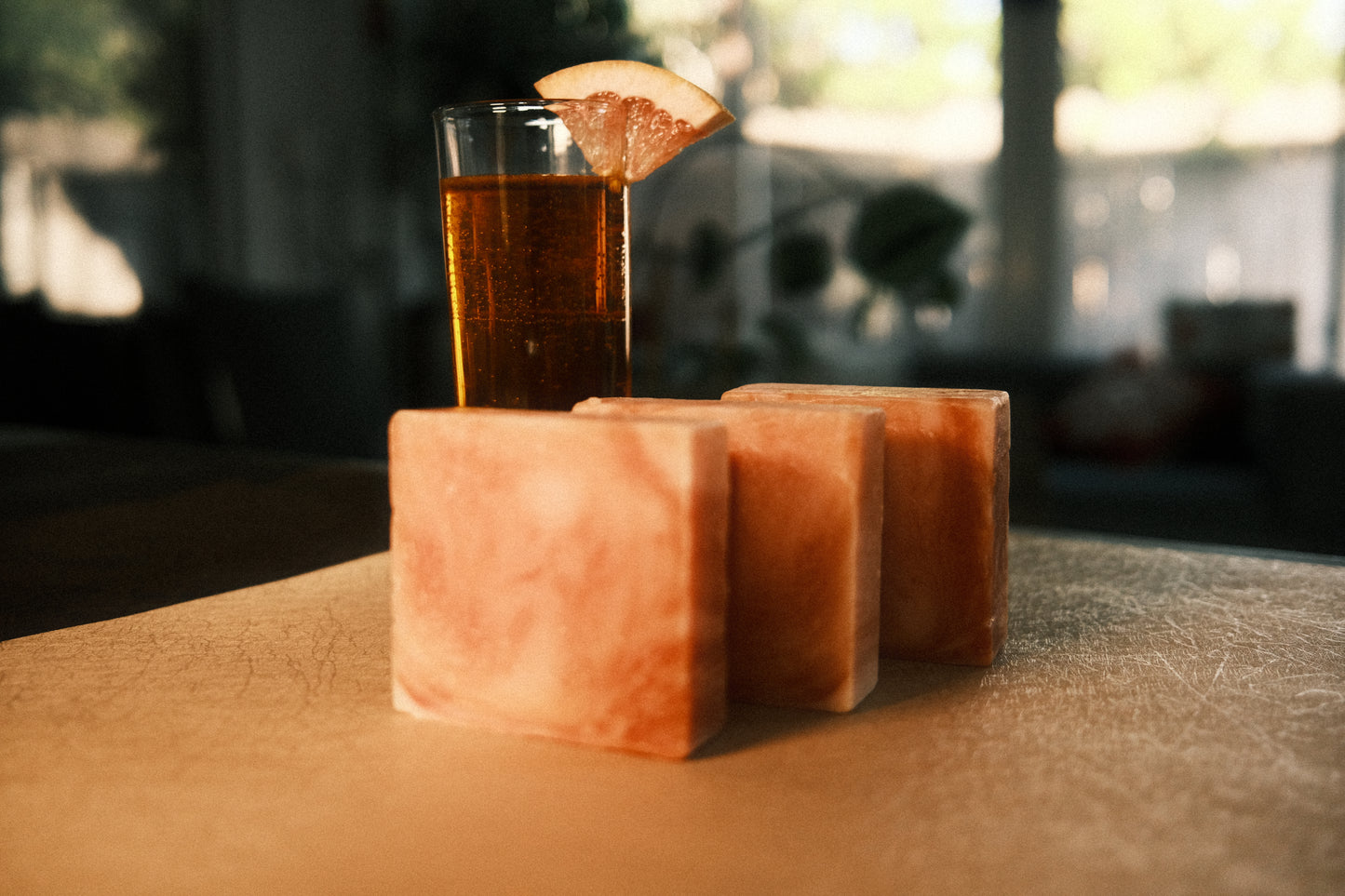 Orange swirled bars of soap standing in ascending order with orange drink in the background