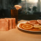 Orange swirled bars of soap on table with orange drink in background and orange slices on place to the right