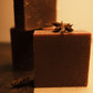 Three bars of brown soap, two stacked in the back and one standing in the front with a half brown and half beige floor. Garnished with star anise