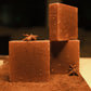 Three bars of brown soap with brown and beige floor, two stacked while one stands in the front, garnished with star anise