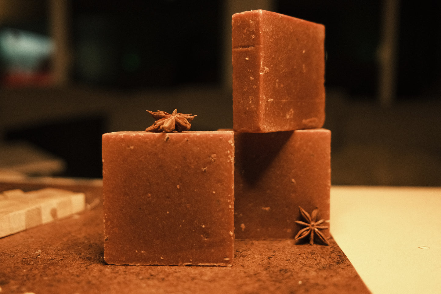 Three bars of brown soap with brown and beige floor, two stacked while one stands in the front, garnished with star anise