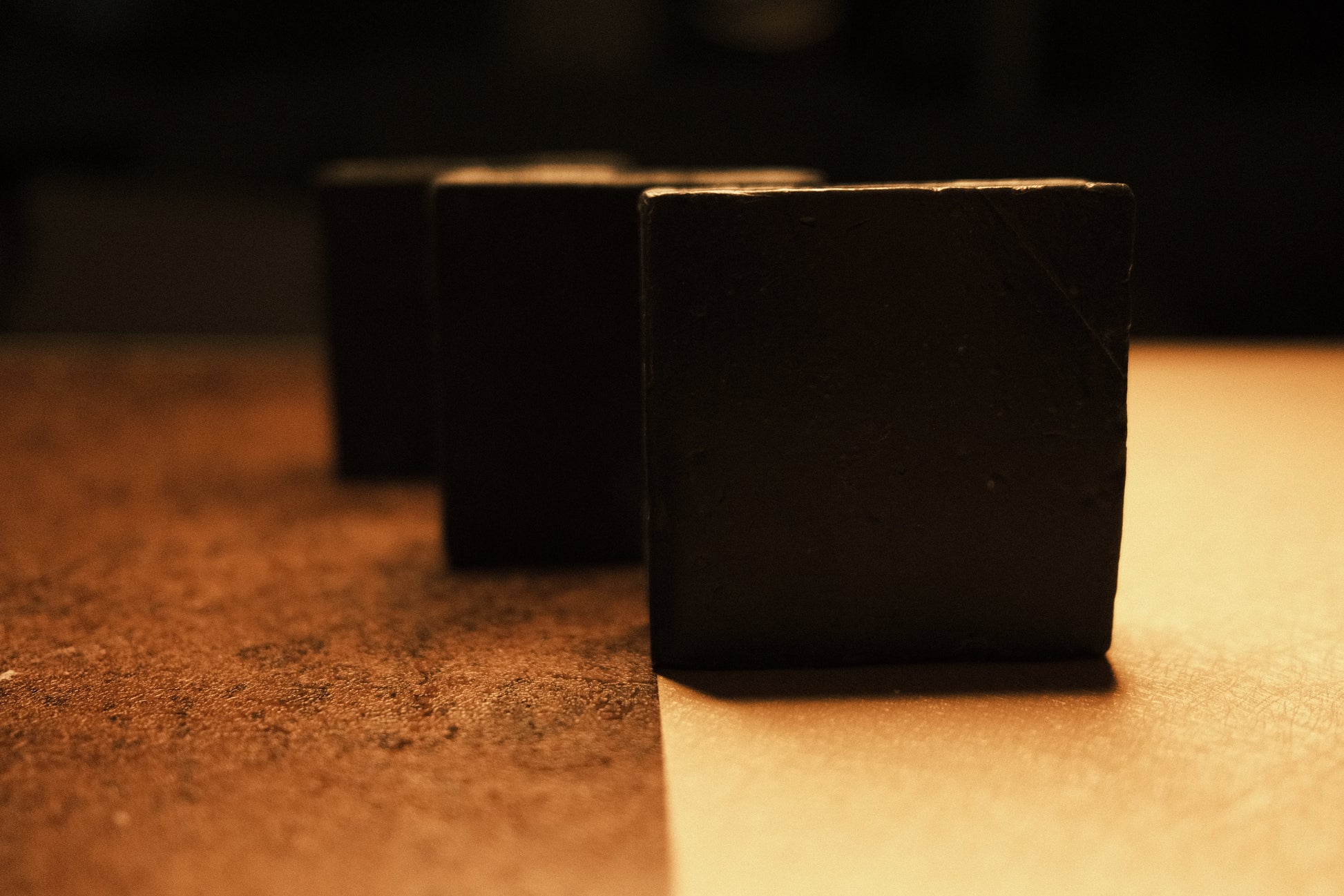 3 bars of soap standing in ascending order with brown and beige floor