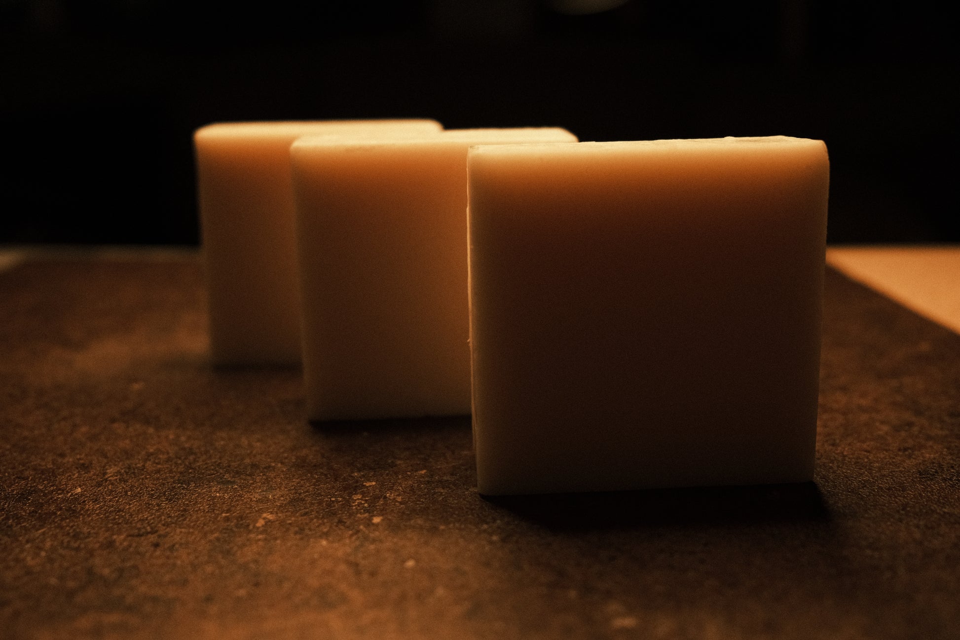 White bars of soap lightly illuminated by warm light, brown floor