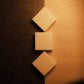 Three bars of plain white soap lay on half beige half brown background, the top two bars angled in diamond shape, the middle sitting flat as a square